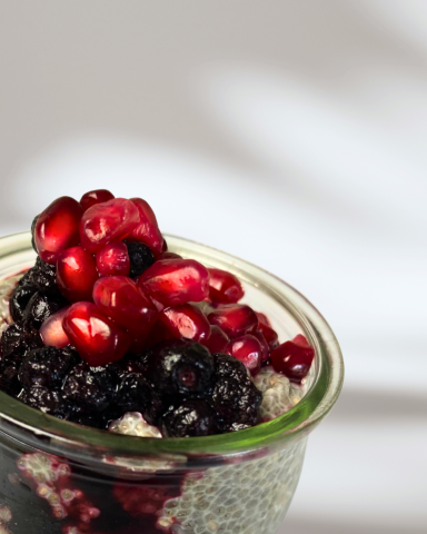 Schichtdessert mit Quinoa, Beeren und Granatapfelkernen in einem Glas.